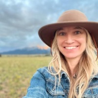 Portrait Kestrel Neathawk wearing hat in field in front of mountains